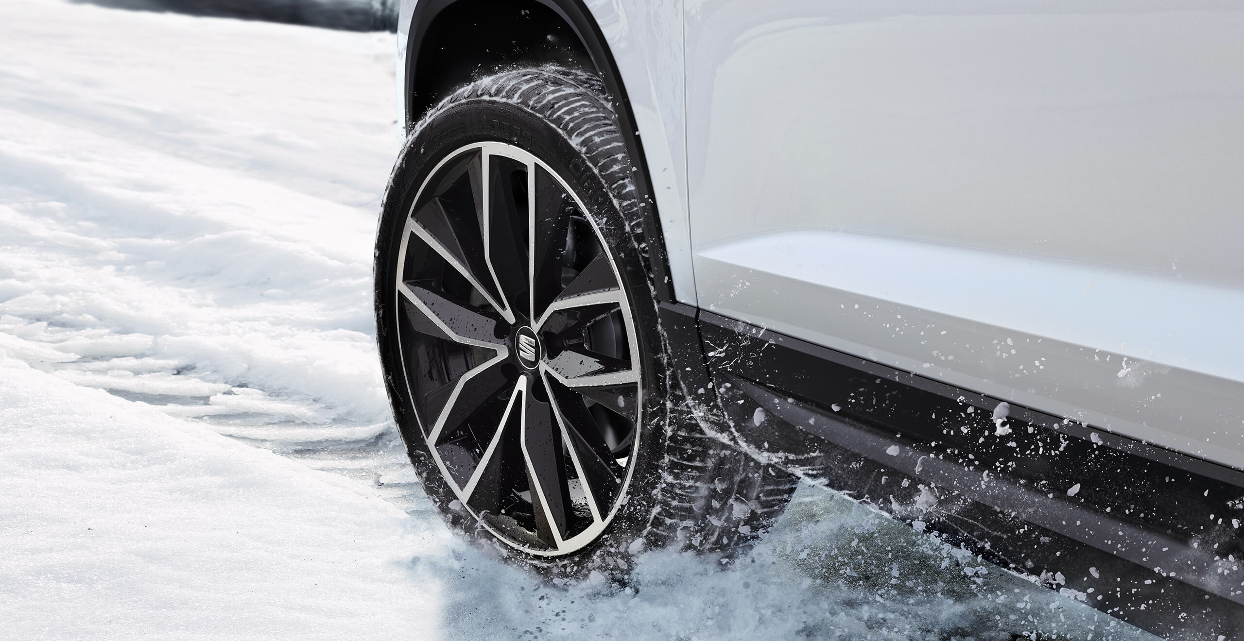 Attēlots SEAT Ateca automašīnas braucošs ritenis uz sniegota ceļa. Droša braukšana un vadība attēlo braukšanu ar SEAT Ateca 4Drive visu riteņu piedziņas sistēmas versiju