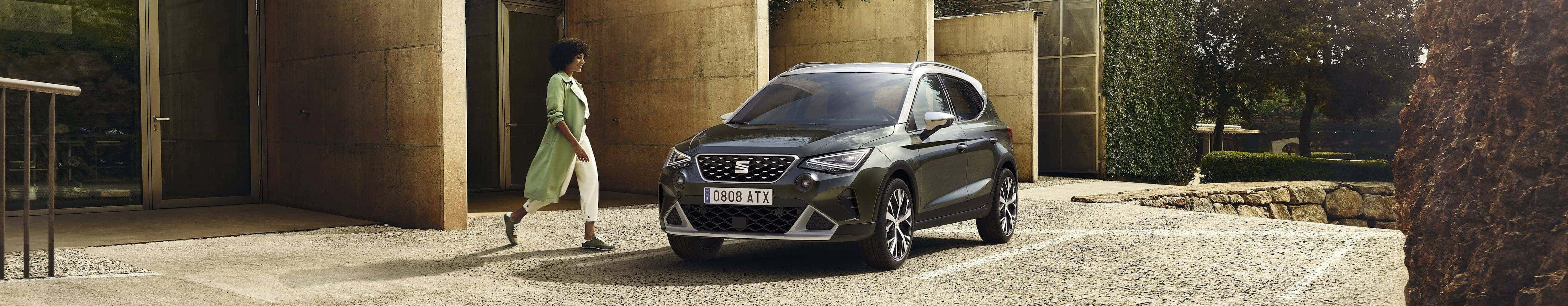 Woman walking to SEAT Arona dark camouflage colour