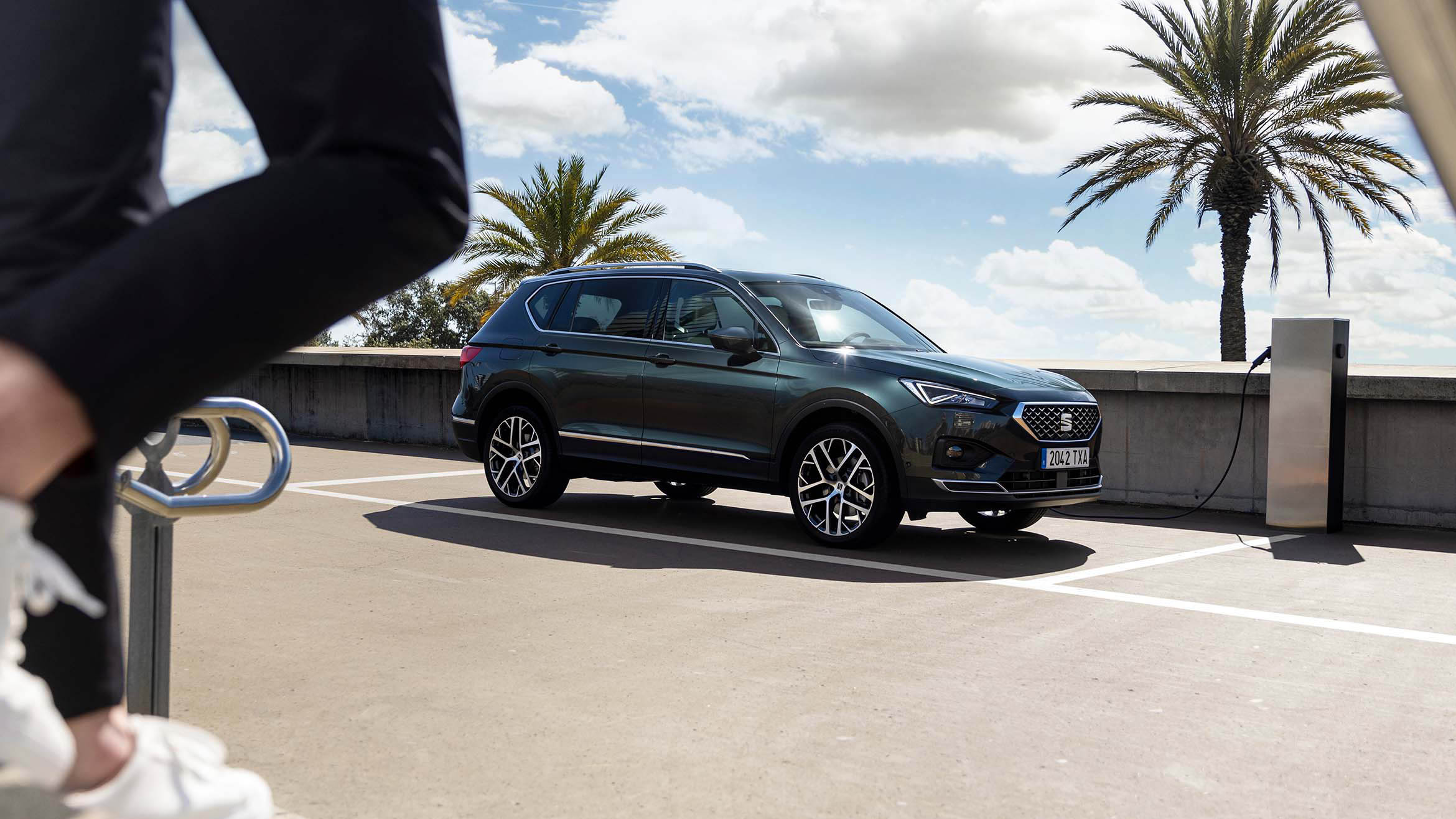 A person walking to the SEAT Tarraco XPERIENCE Dark Camouflage colour while charging