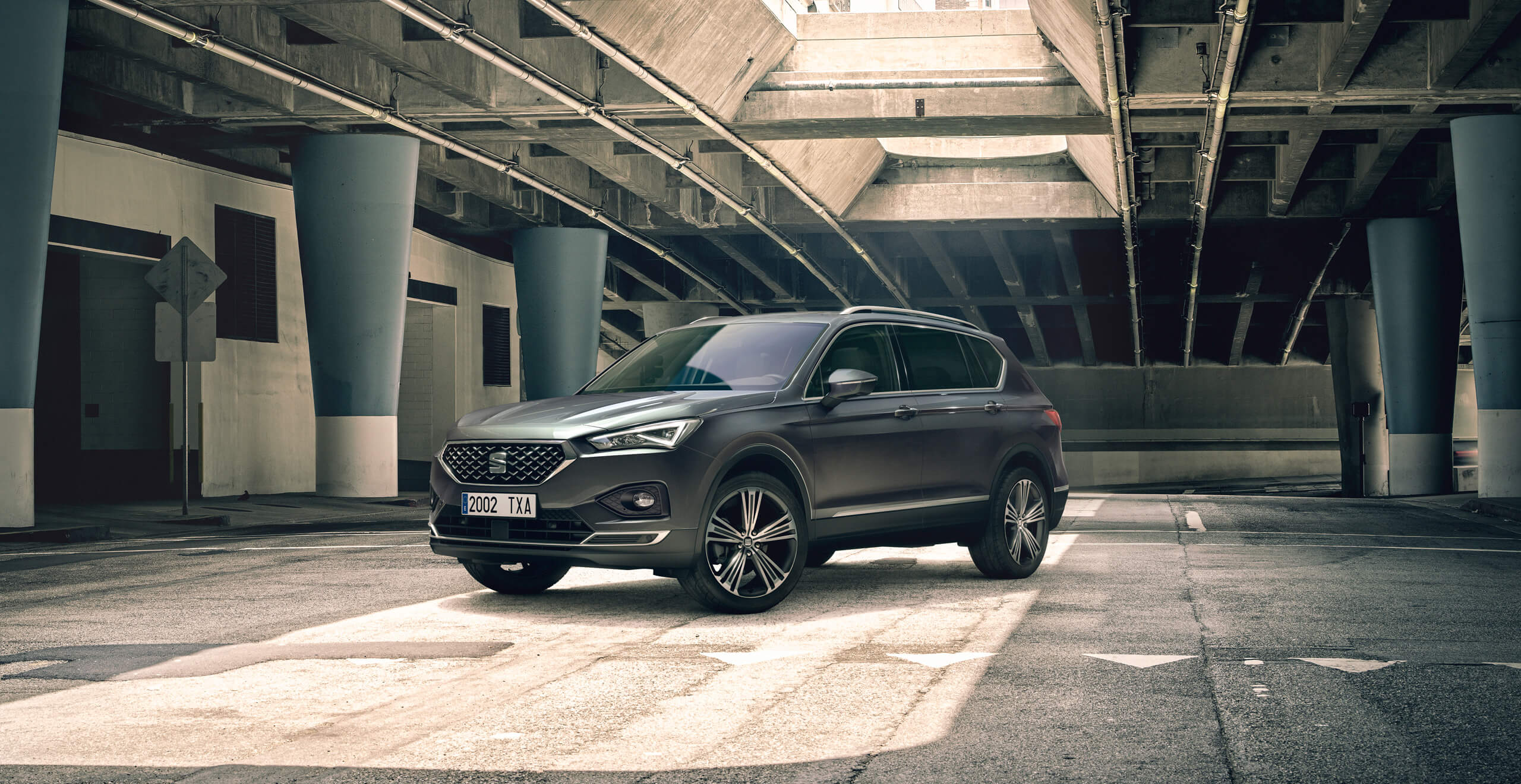 SEAT Arona crossover SUV driving in an urban street lined with palm trees