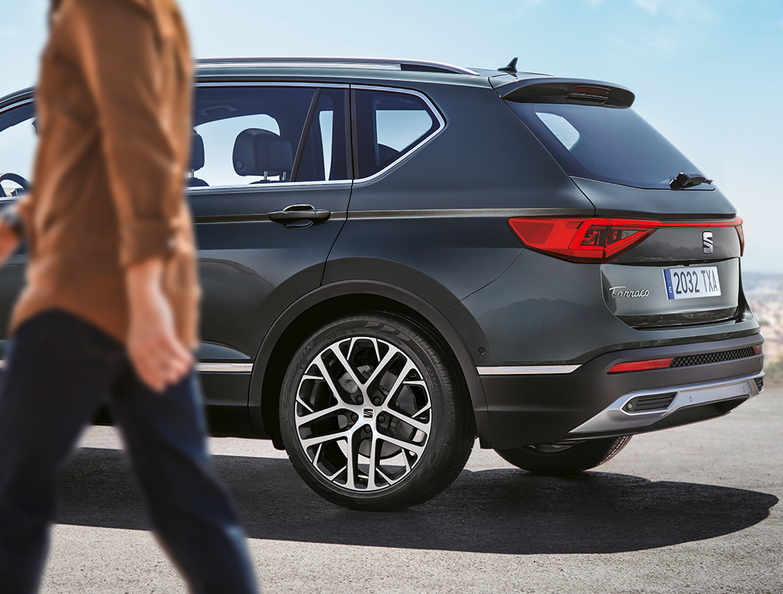 Man passing by the SEAT Tarraco Dark Camouflage colour with 20-inch nuclear grey alloy wheels  